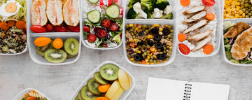 Healthy meal prep boxes with salads fruits and chicken